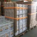 2 orange StrapPRO reusable strapping system by Lynksols wrapping a pallet loaded with boxes.