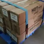 Our reusable Strap called Strap Pro Ultra in blue color being used by a client, securing a load in a blue pallet.